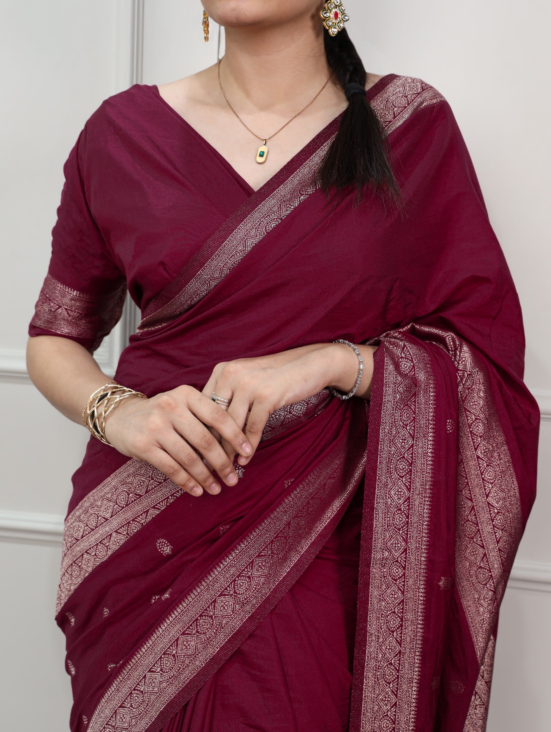 Woman wearing a maroon saree with intricate patterns on a white background