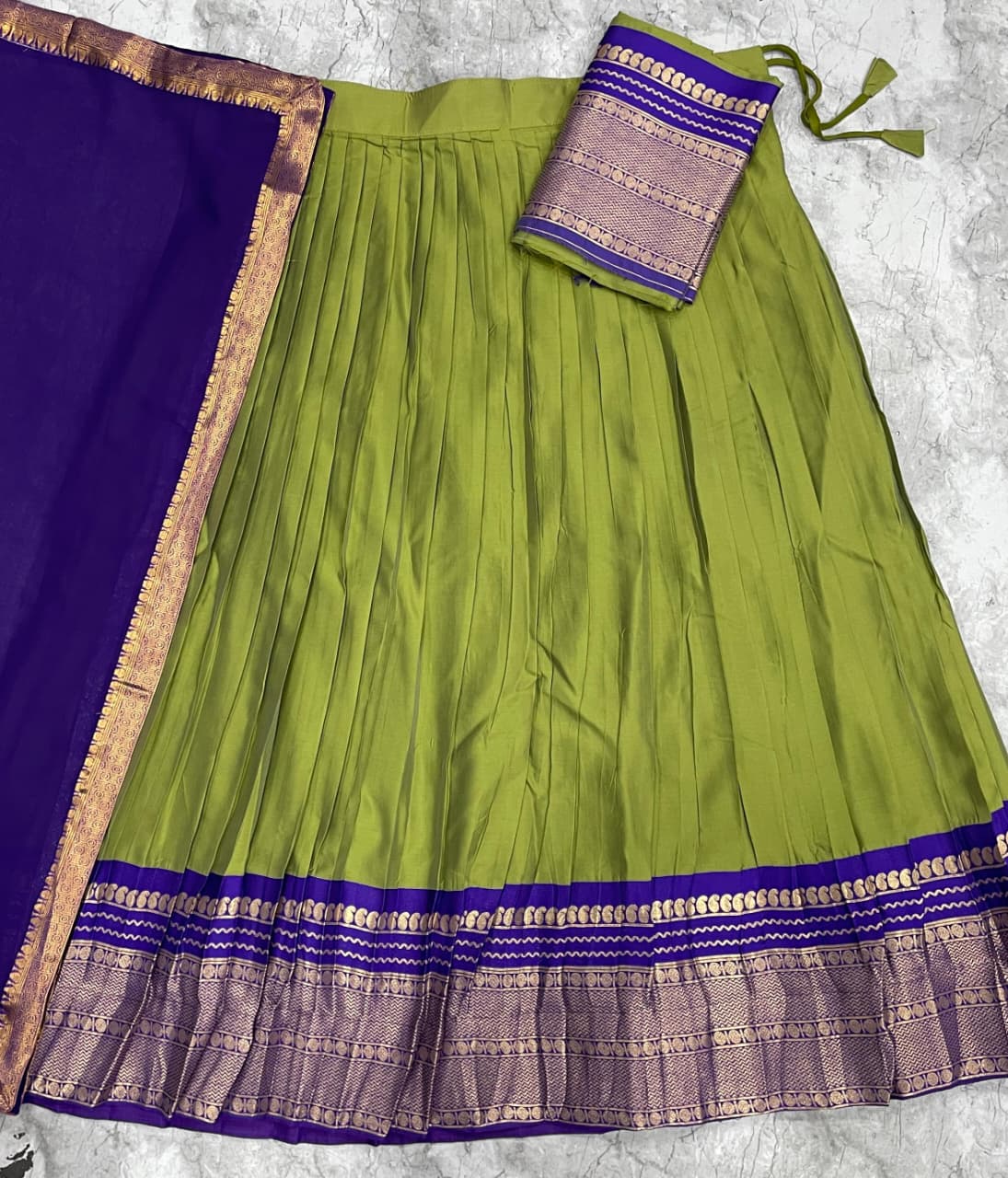 Parrot Green saree with purple border and matching blouse on a textured surface