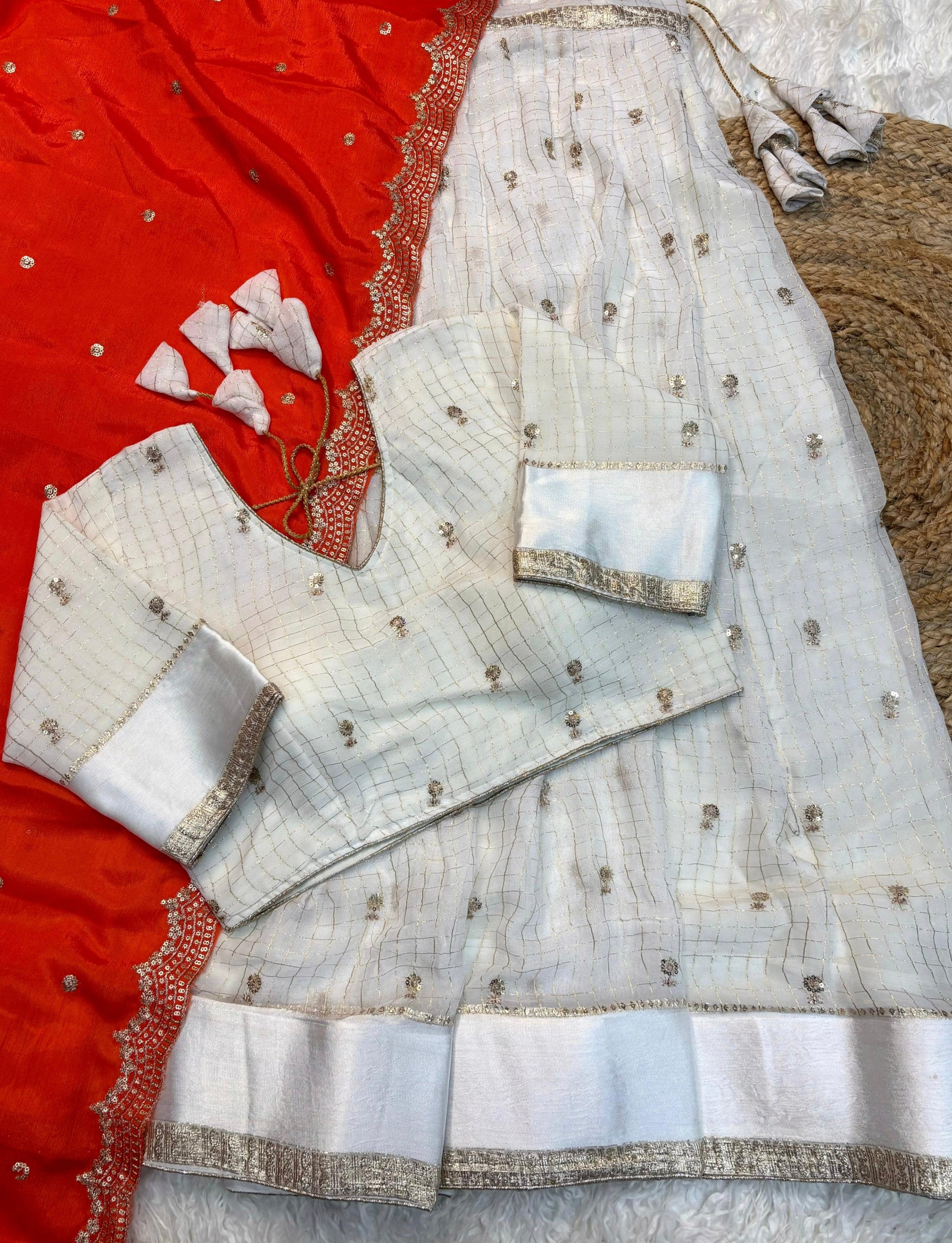 Orange embroiderey saree with white border on a textured surface