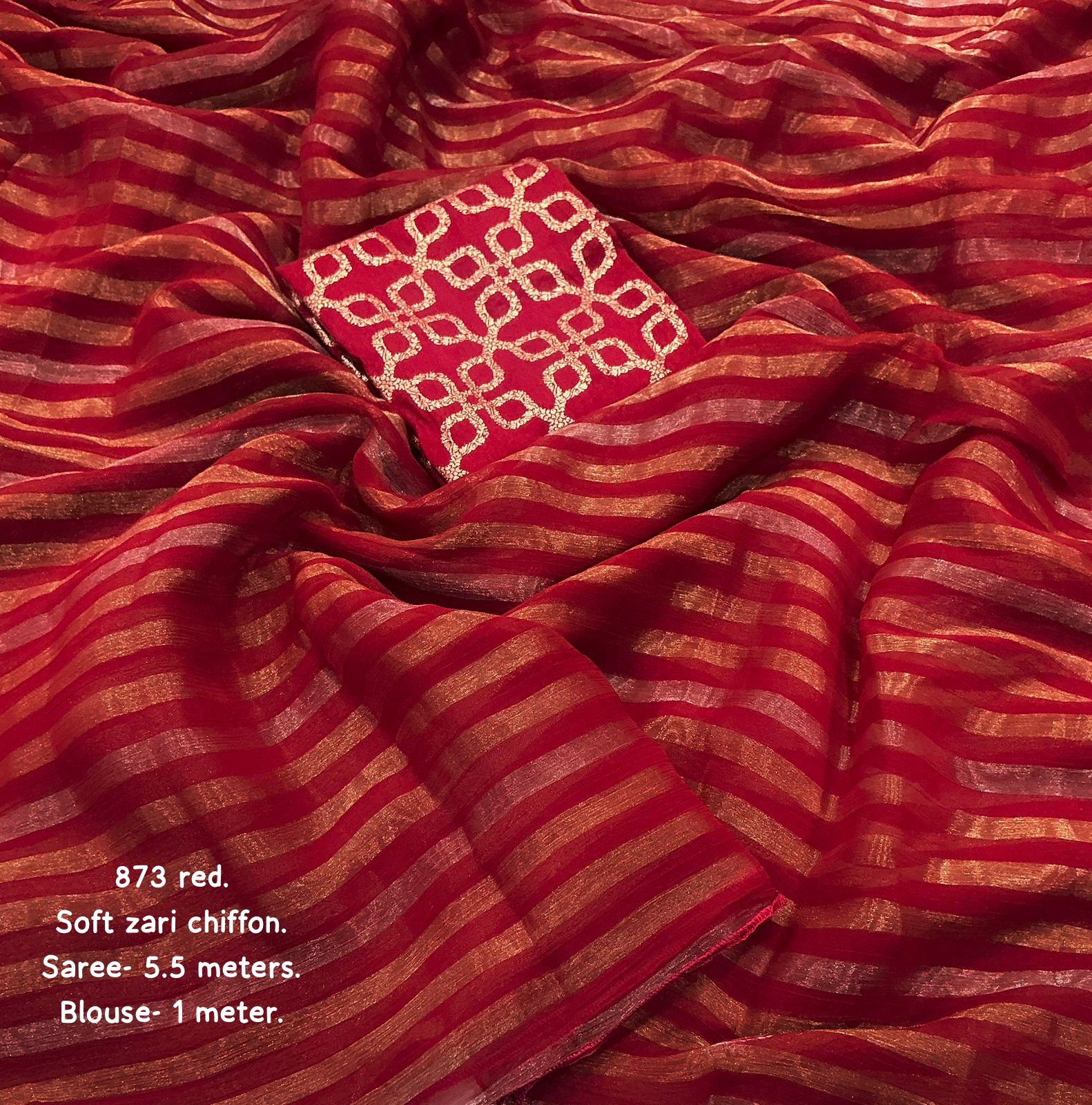 Red zari chiffon saree with intricate design, displayed on a matching fabric background.