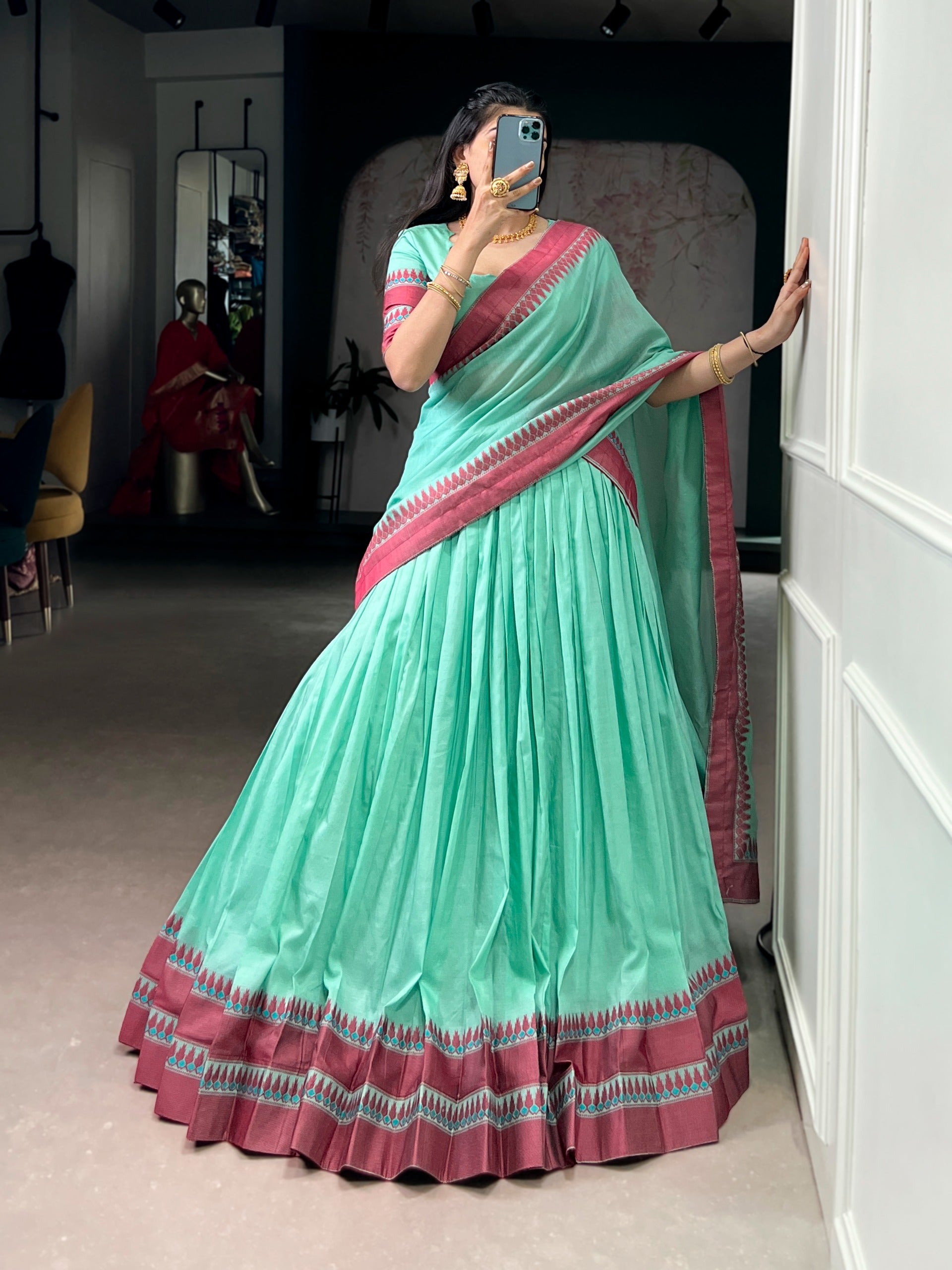 Woman wearing a cyan saree with border in a room.