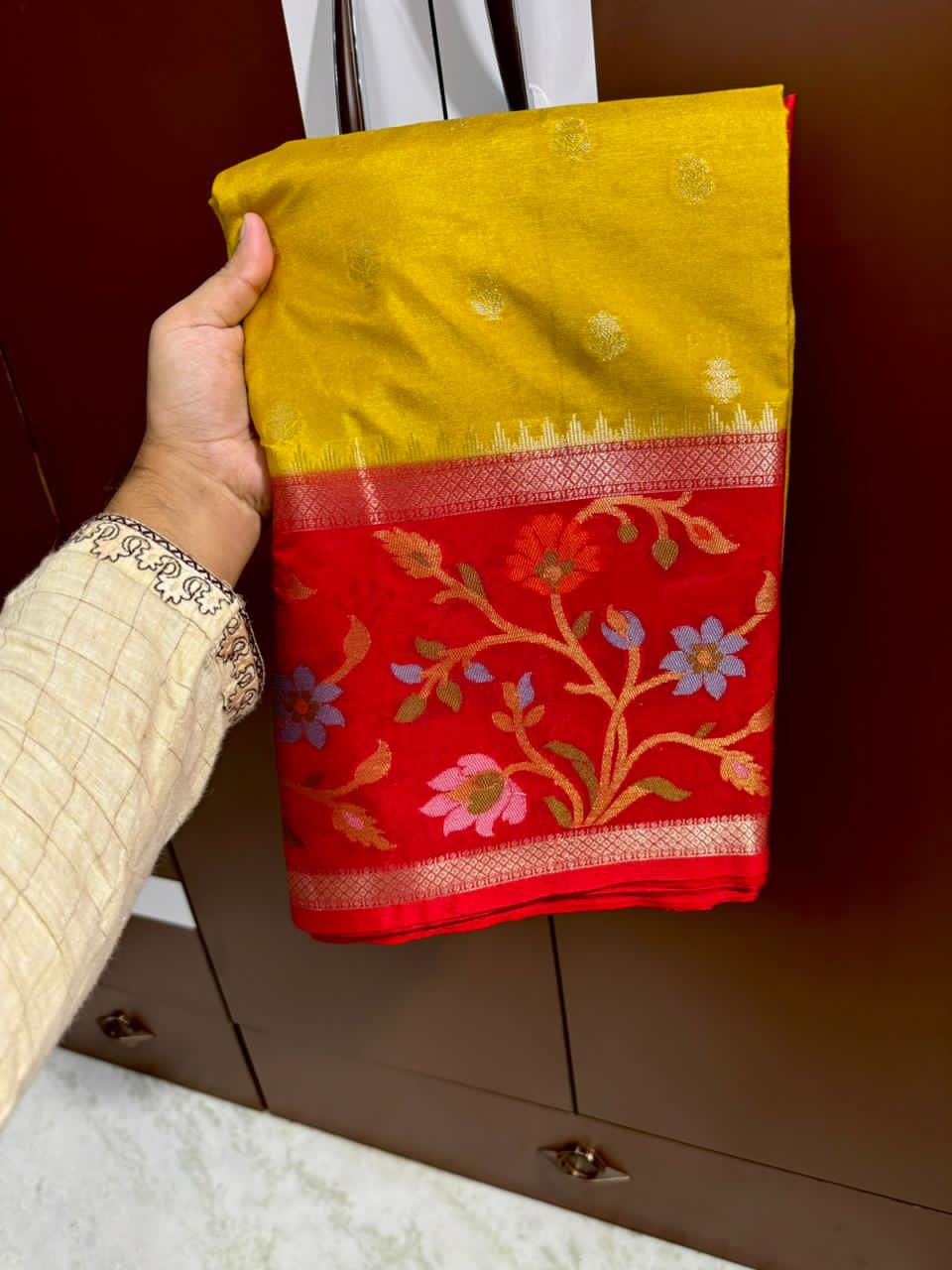 Mustard Yellow ellow fabric with floral patterns against a brown cabinet background