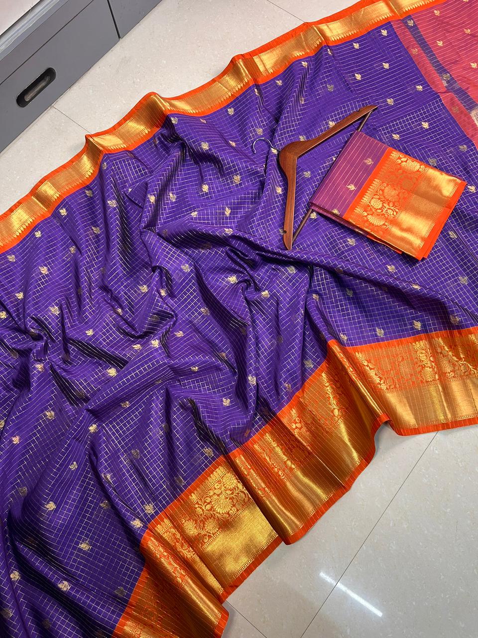 Purple saree with gold border on a white floor