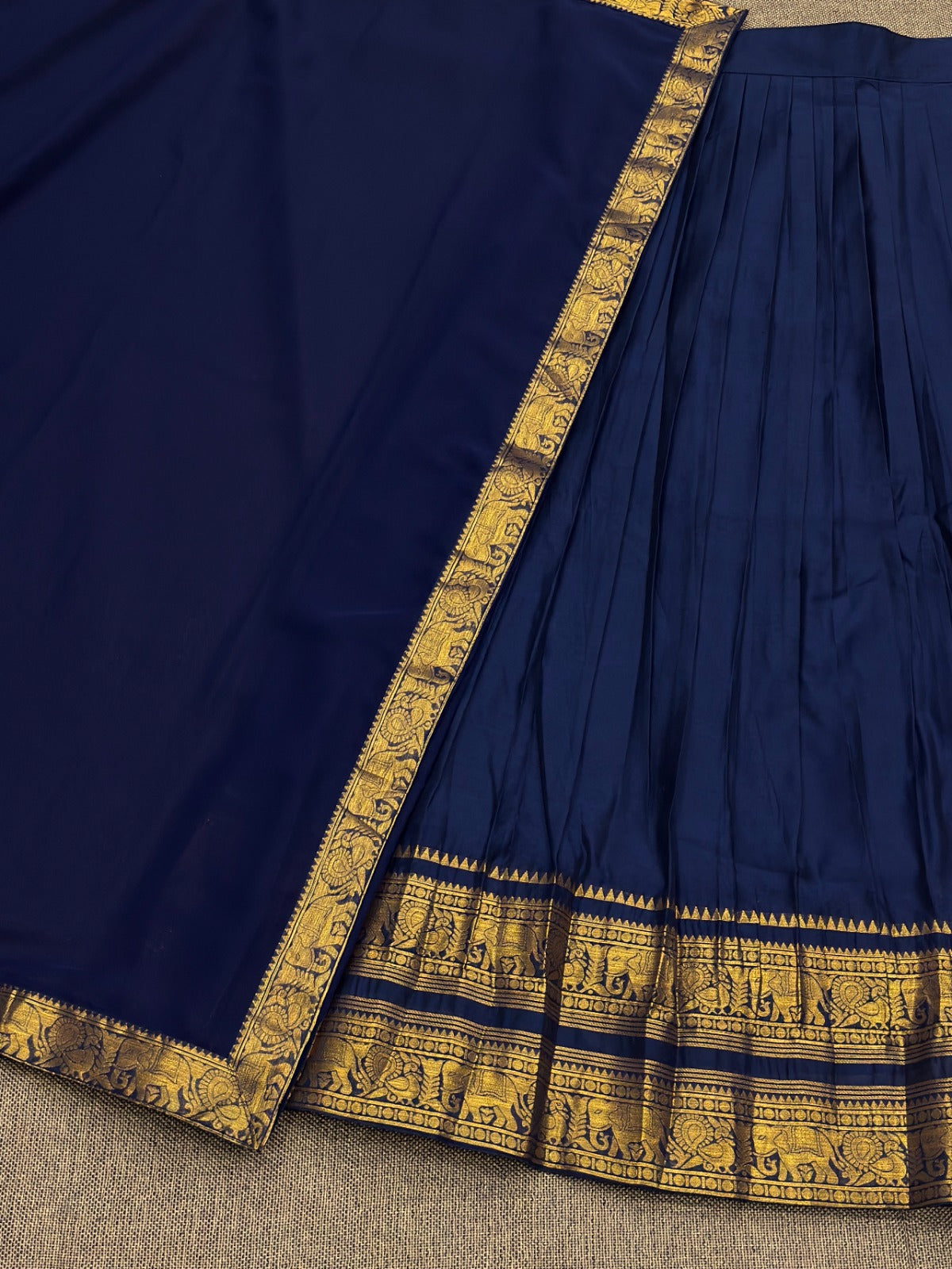 Navy blue saree with gold border on a textured surface