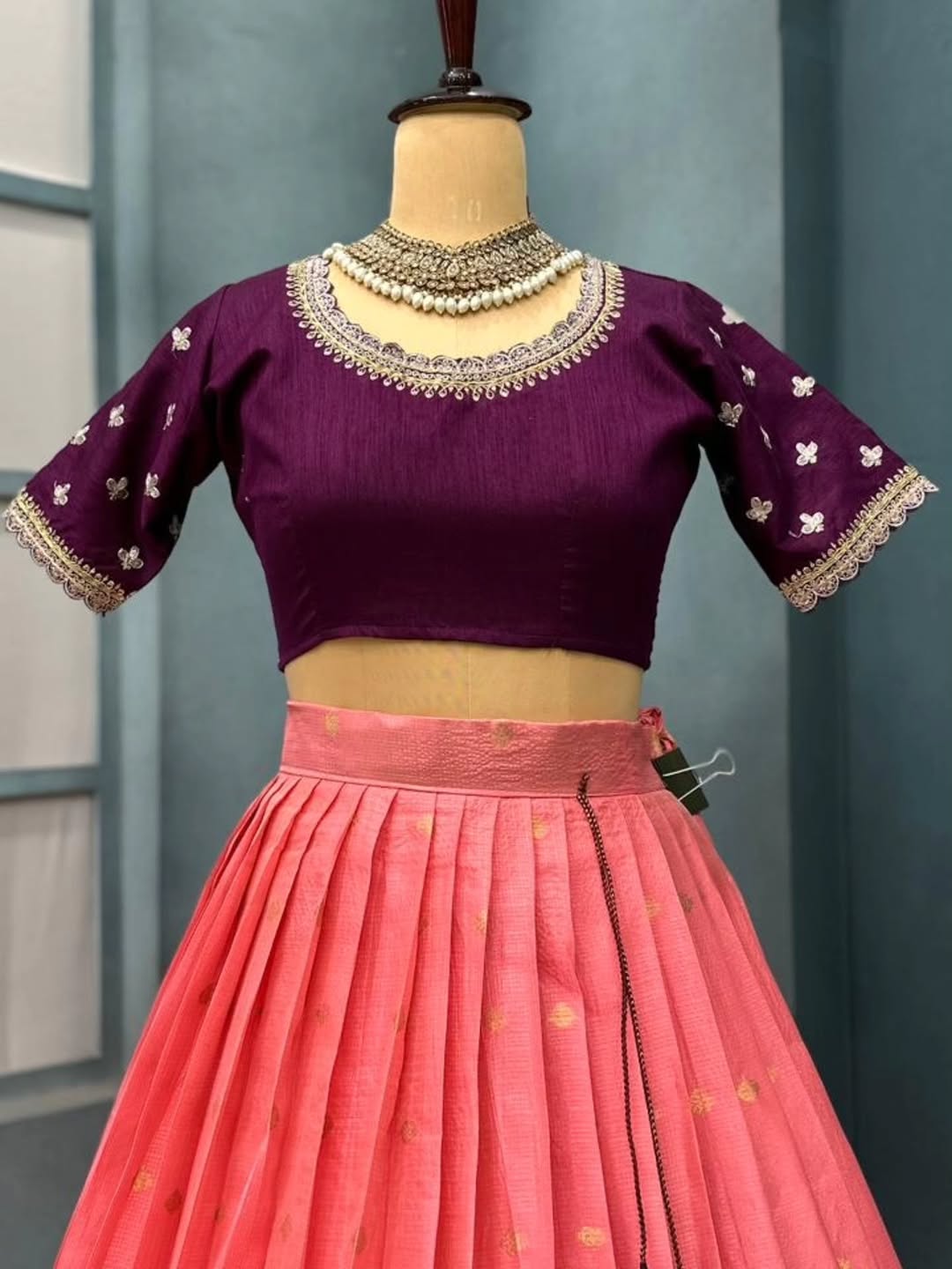 Peach lehanga on a mannequin against a gray background