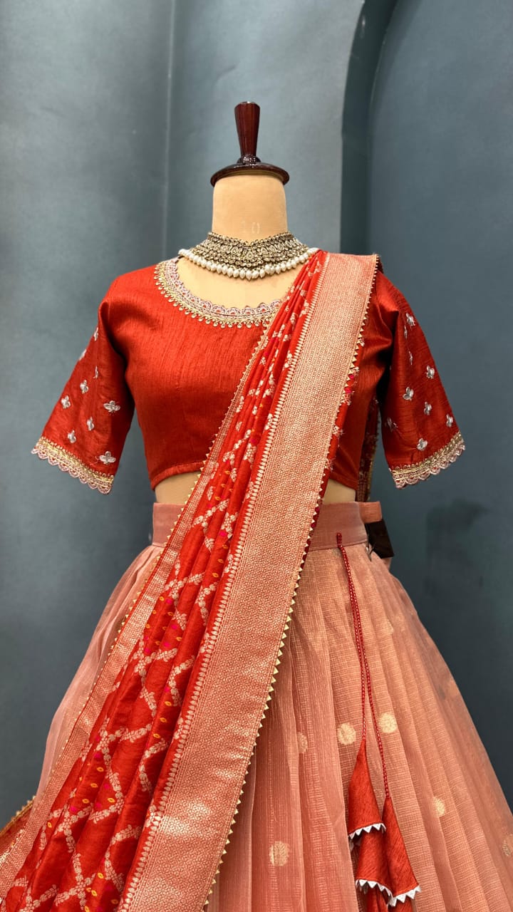 Light orange traditional outfit with intricate patterns on a mannequin against a gray background
