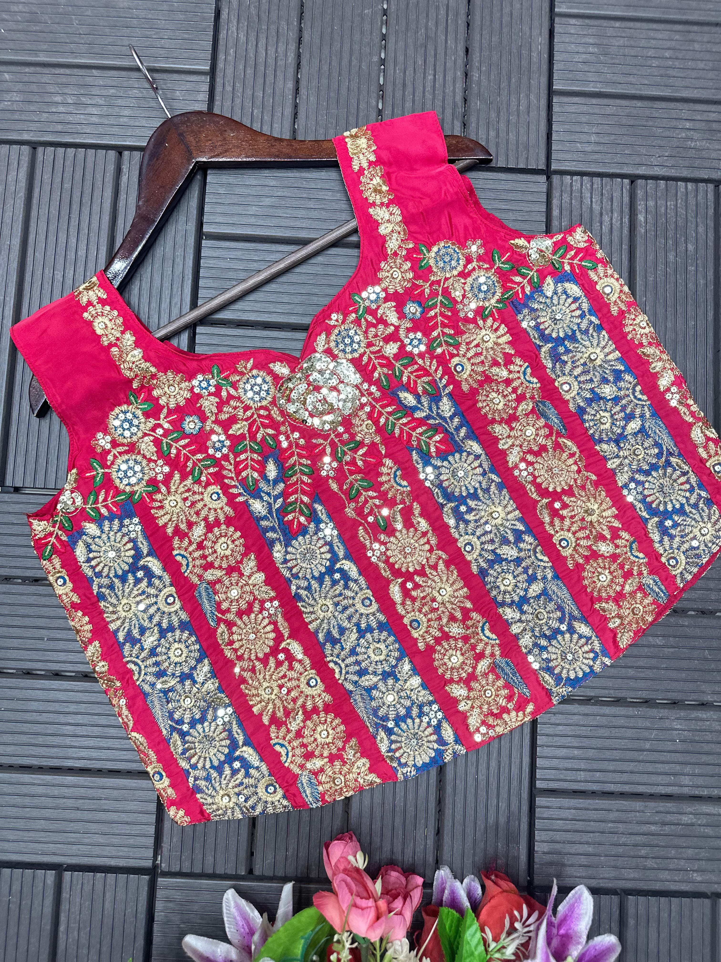 Embroiderey pink blouse with floral patterns on a wooden hanger against a gray texture background.