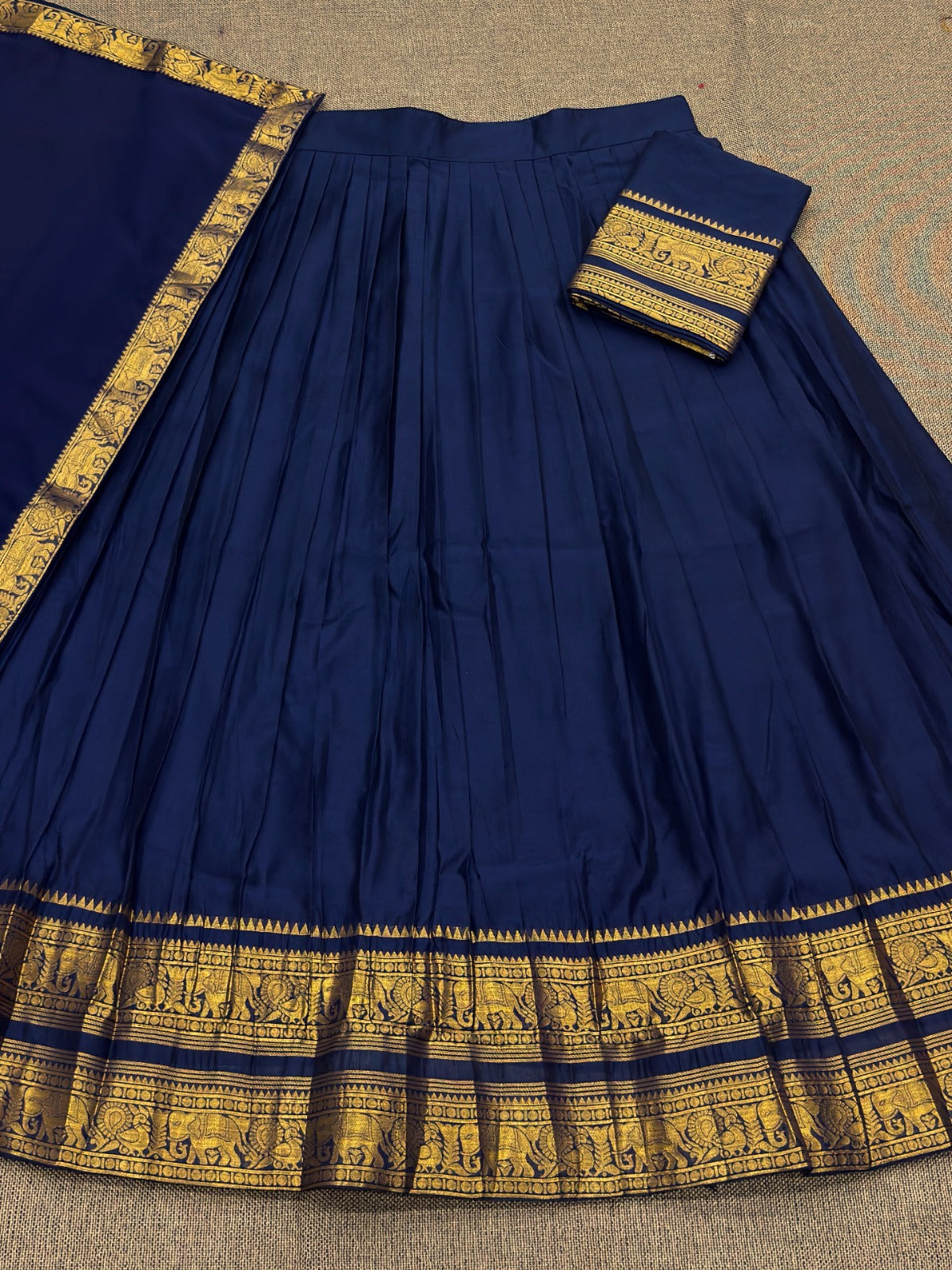 Navy Blue saree with gold border on a textured surface