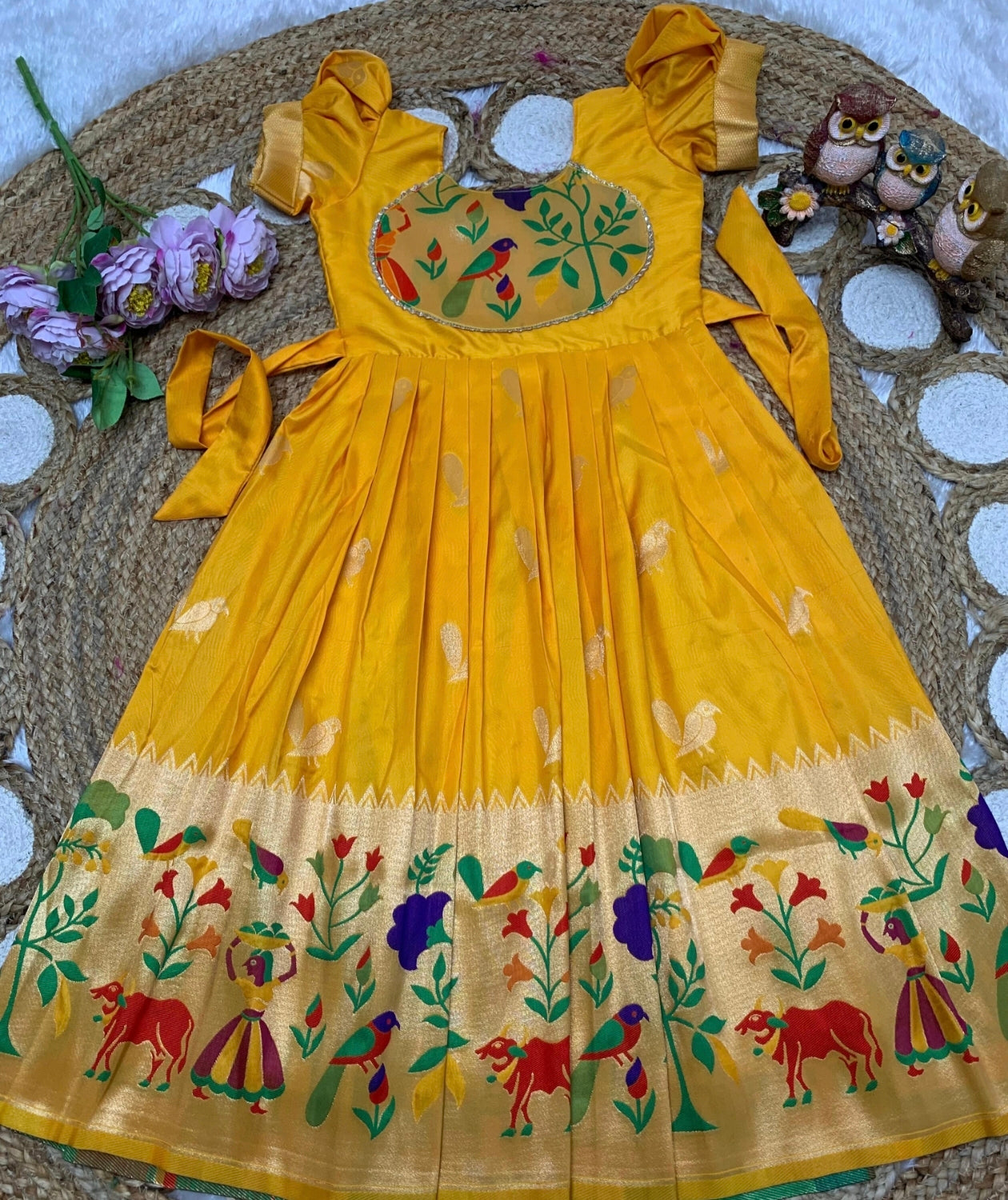 Yellow dress with floral and animal patterns on a texture surface.
