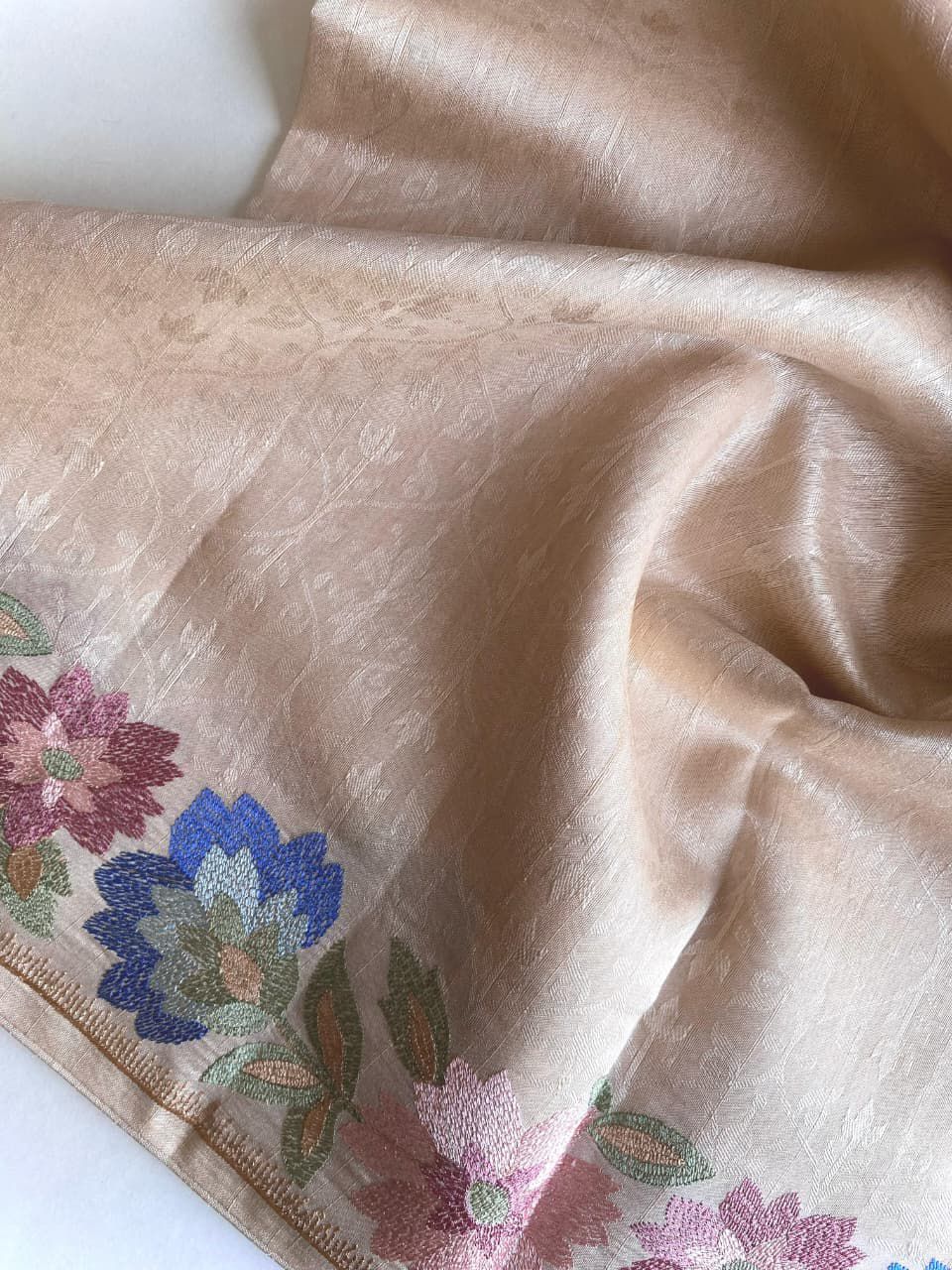 Beige fabric with floral embroidery on a white background