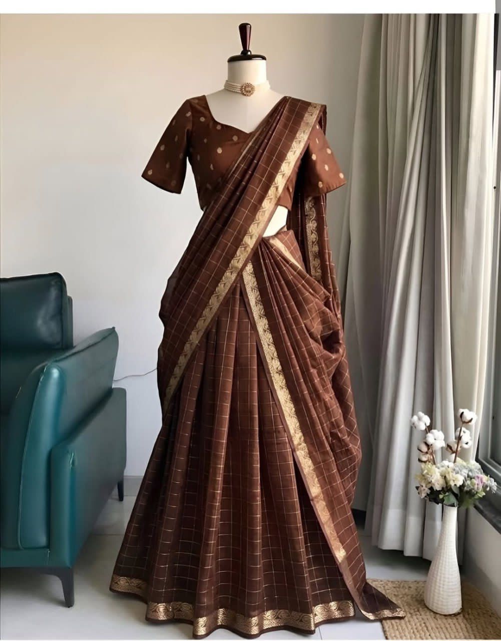 Brown saree with gold border on a mannequin against a neutral background