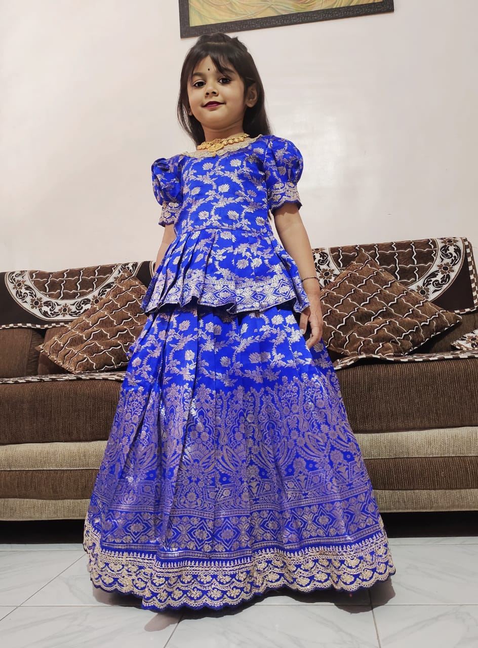 Child wearing a Royal blue traditional outfit in a living room setting