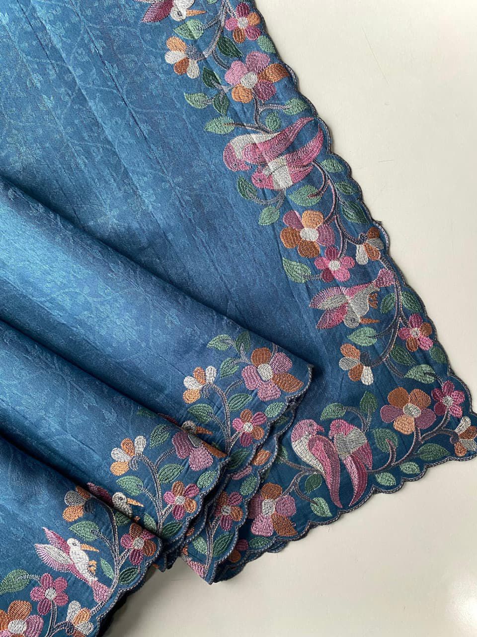 Blue fabric with floral embroidery on a white background