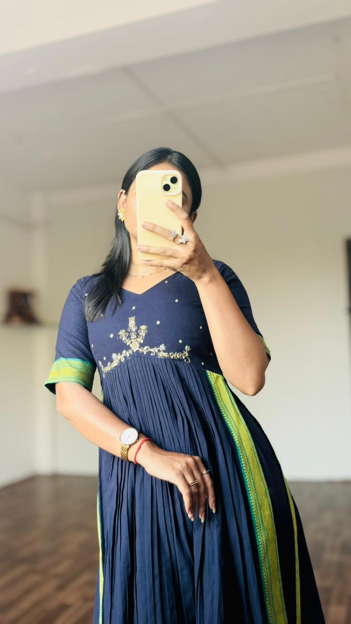 Person wearing a Navy blue dress with green accents in a room.