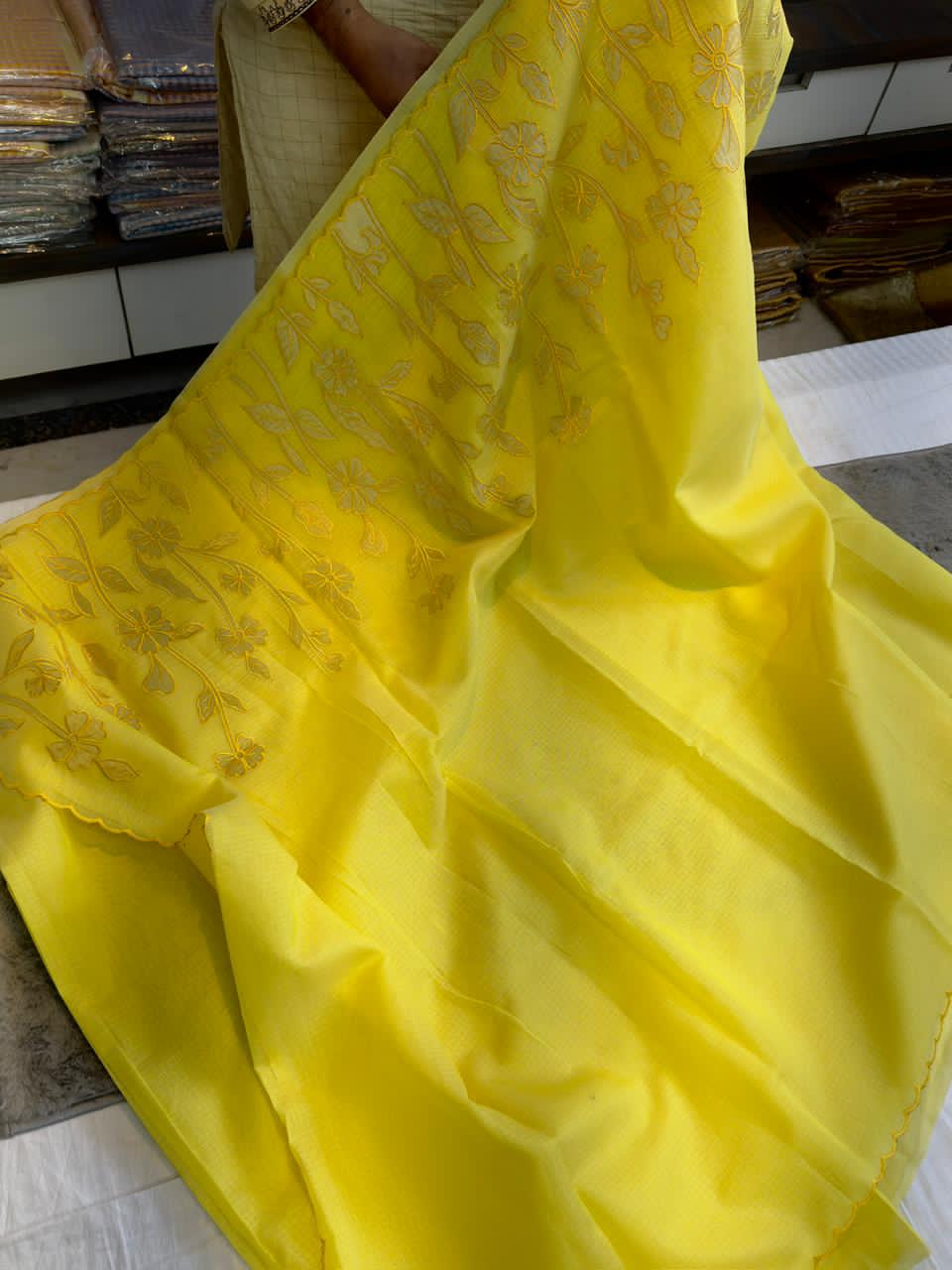 Yellow fabric with floral patterns on a tiled floor.