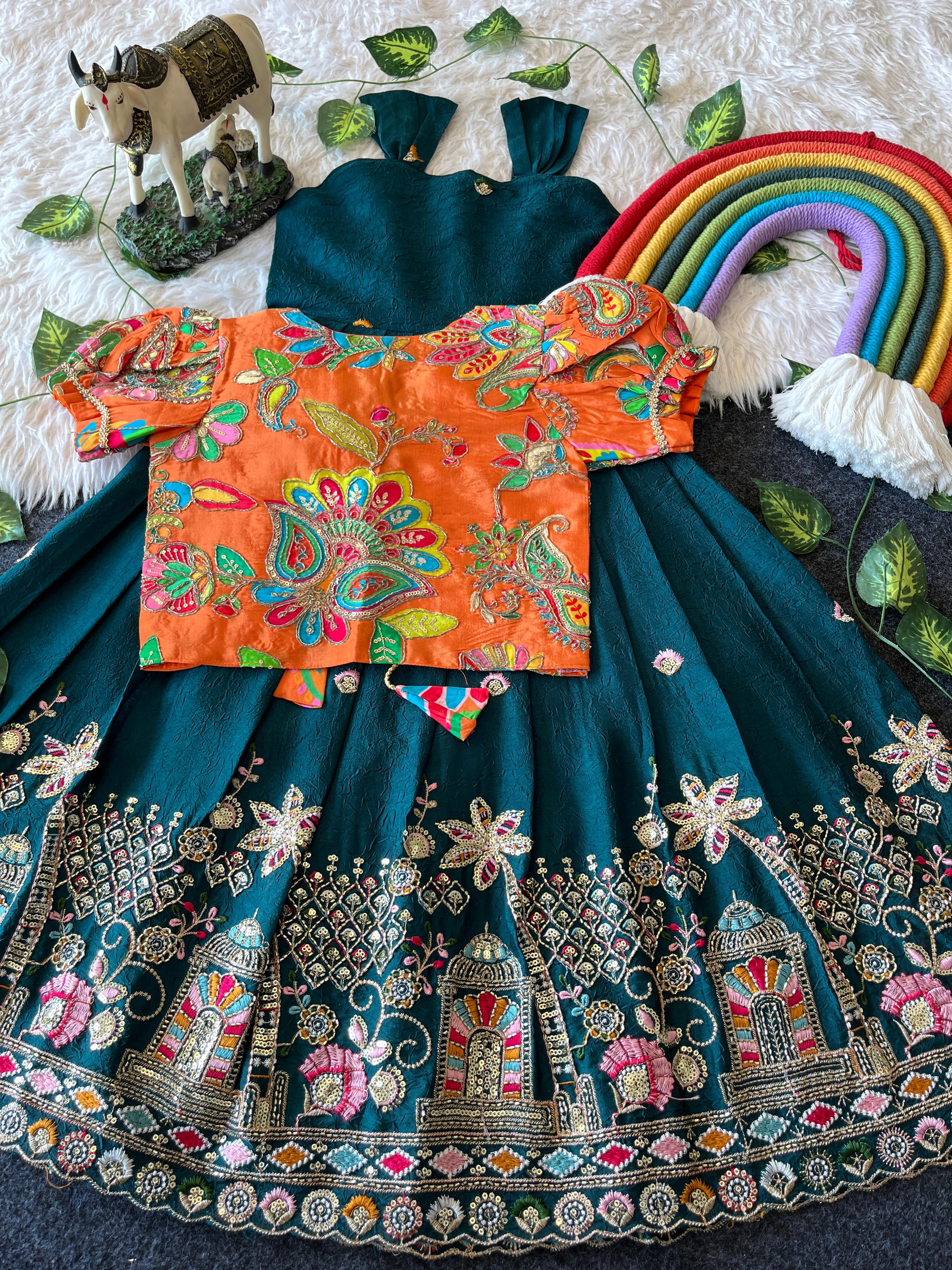 Traditional Rama green embroidered outfit with colorful top and teal skirt on a textured surface.