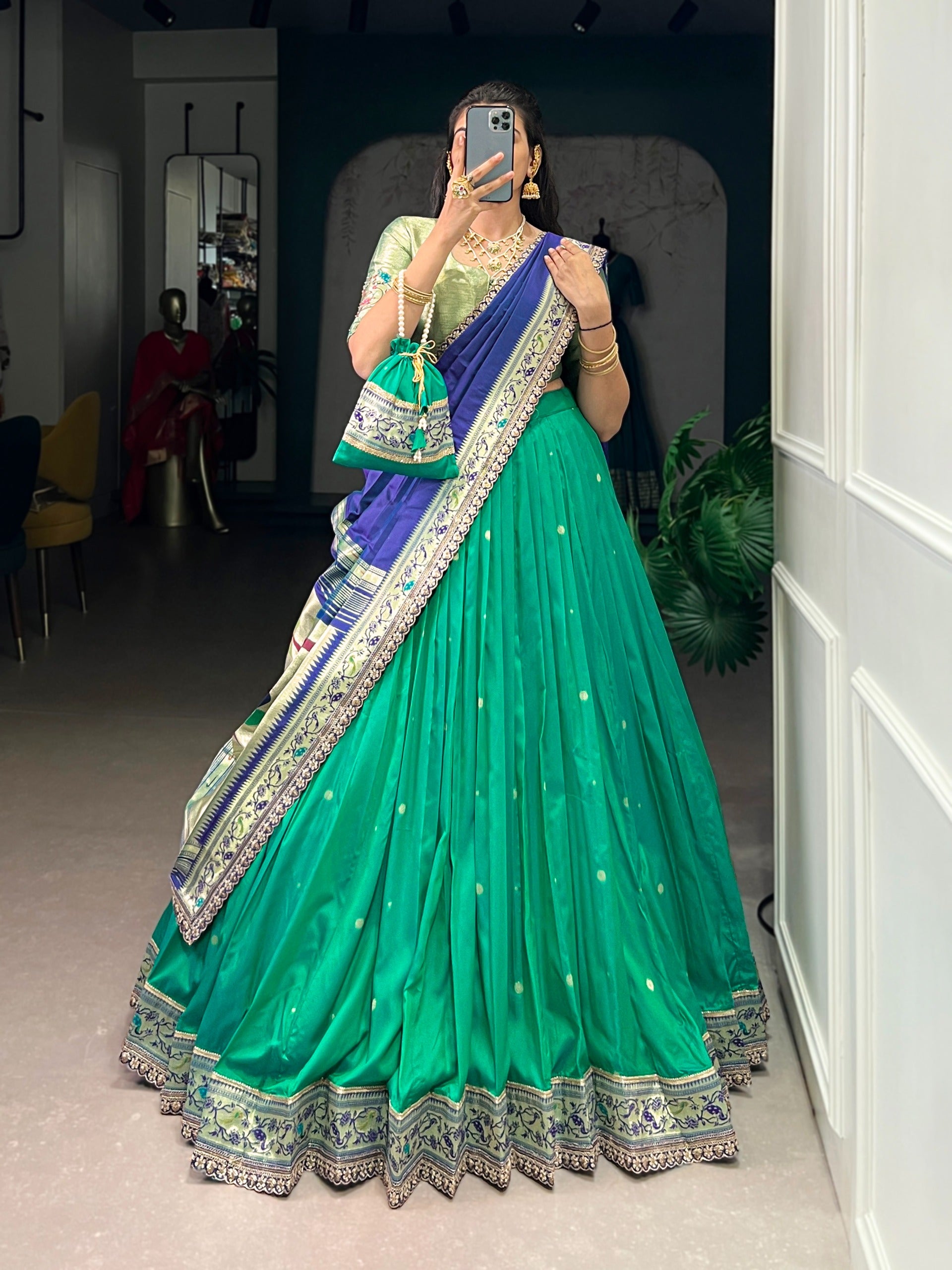Person wearing a cyan saree with  blouse, standing indoors.