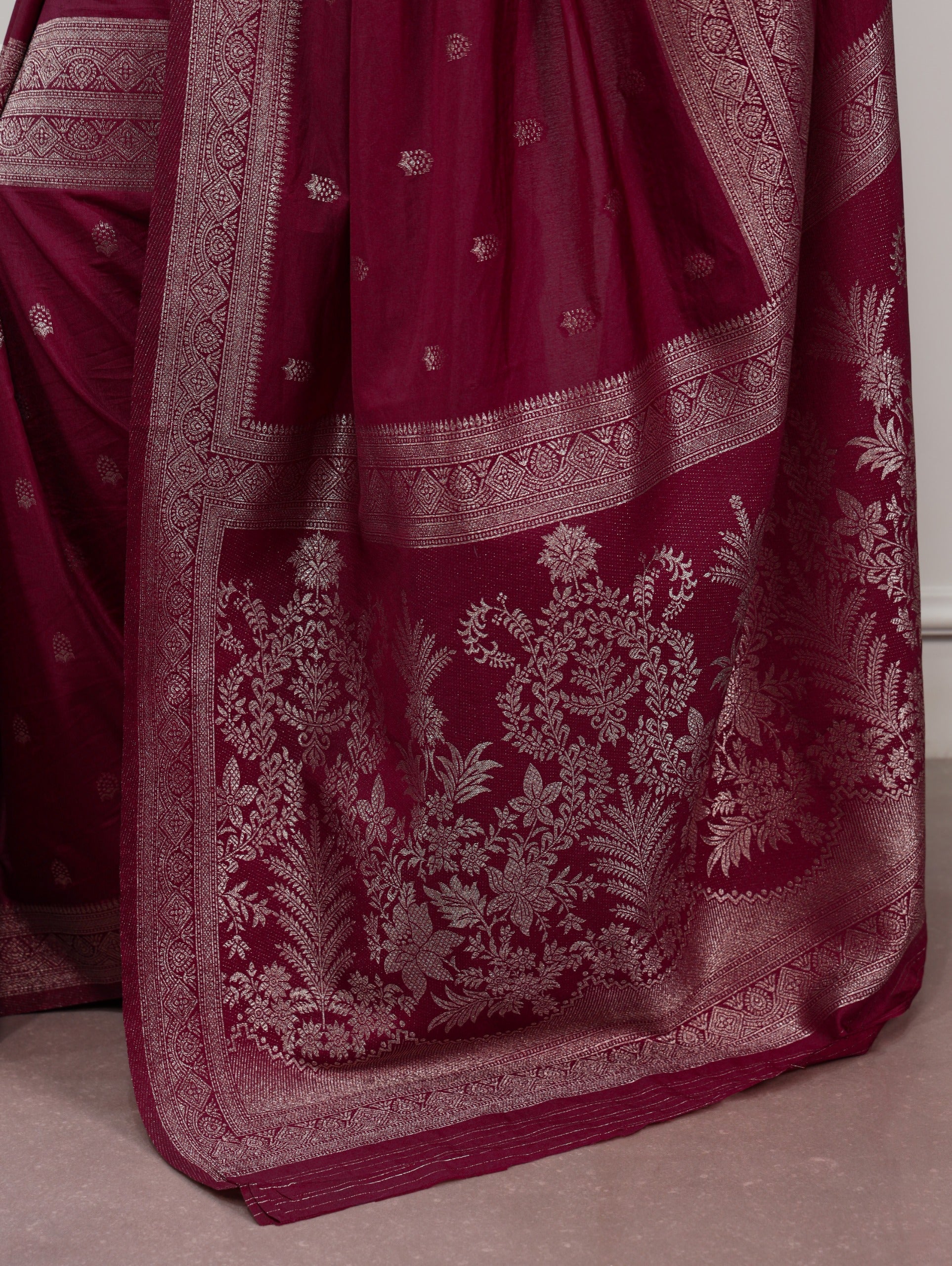Maroon fabric with intricate silver embroidery on a neutral background