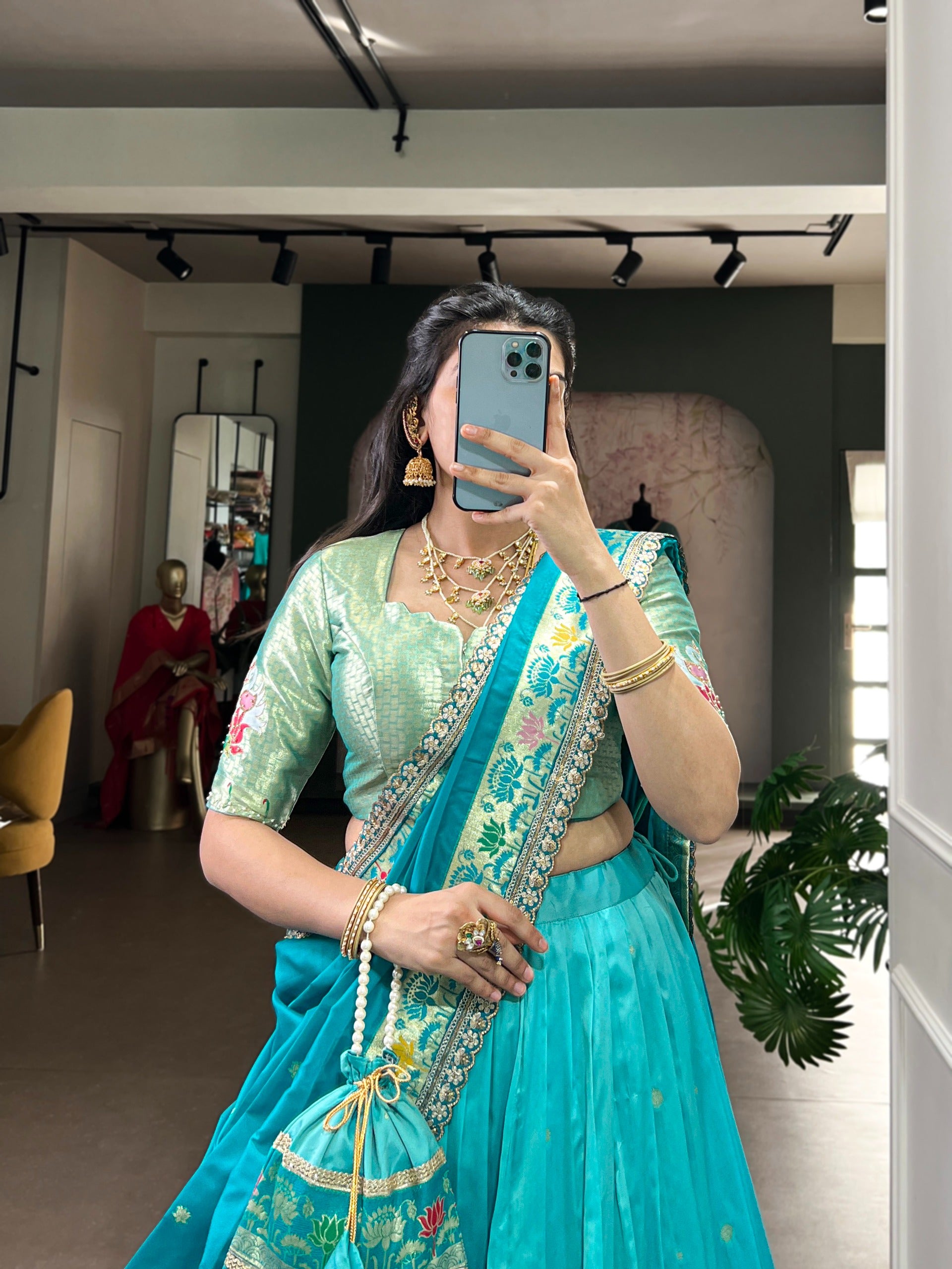 Woman taking a mirror selfie wearing a sky blue traditional outfit with jewelry.