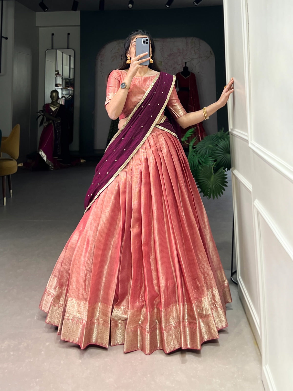 Person wearing a peach saree with a  blouse in a room.