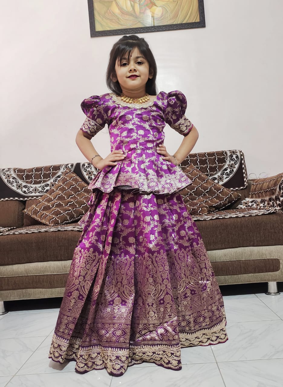 Child wearing a purple traditional outfit in a living room setting