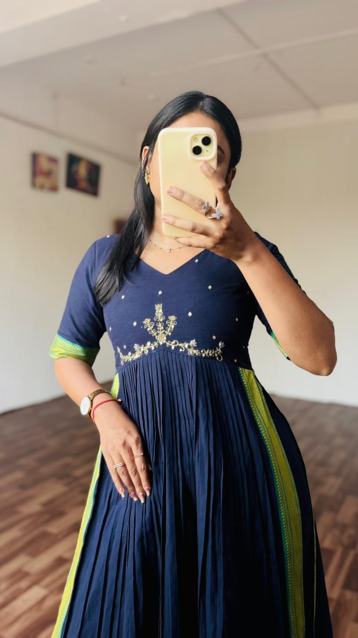 Woman taking a mirror selfie wearing a navy blue dress with green accents.