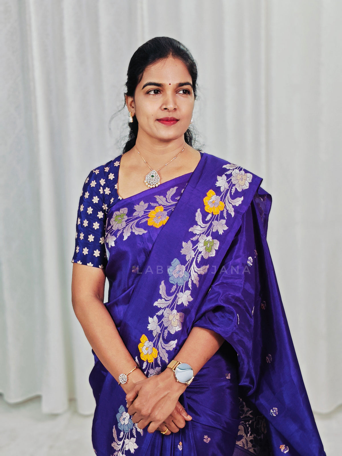 A woman wearing a purple silk saree, paired with a matching embroidered blouse