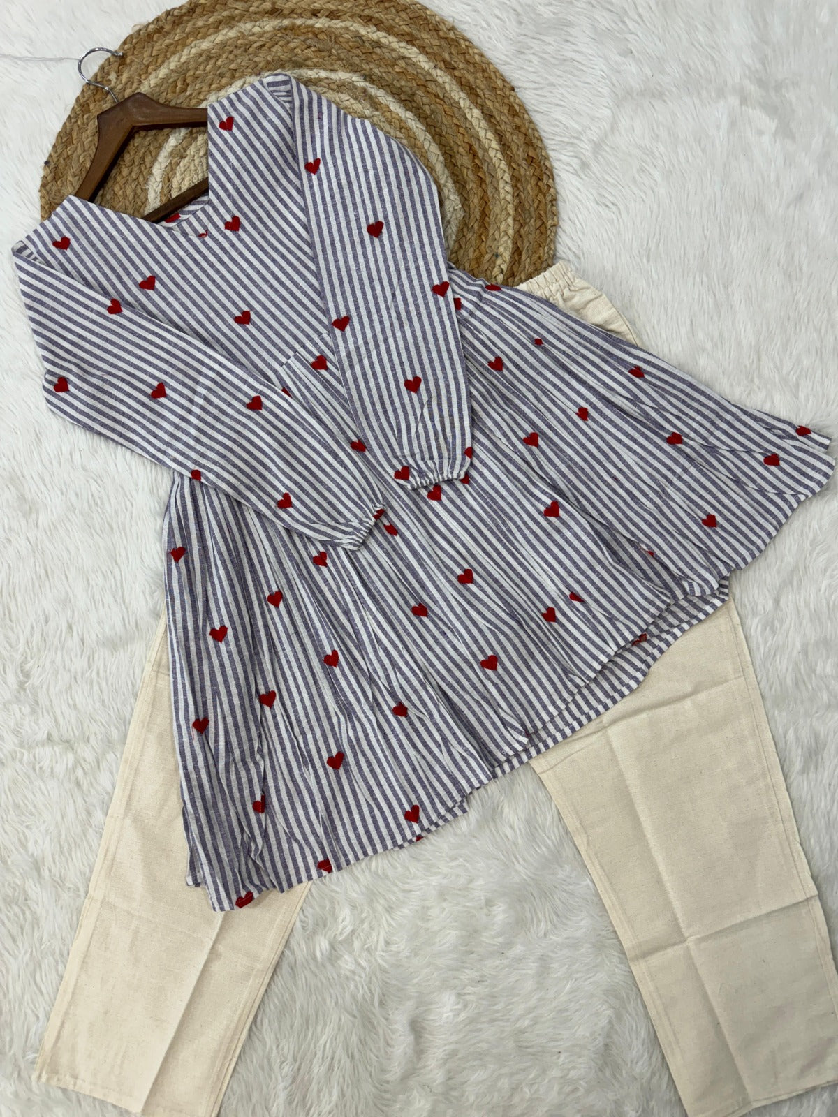 Striped gray shirt with red heart patterns on a textured surface