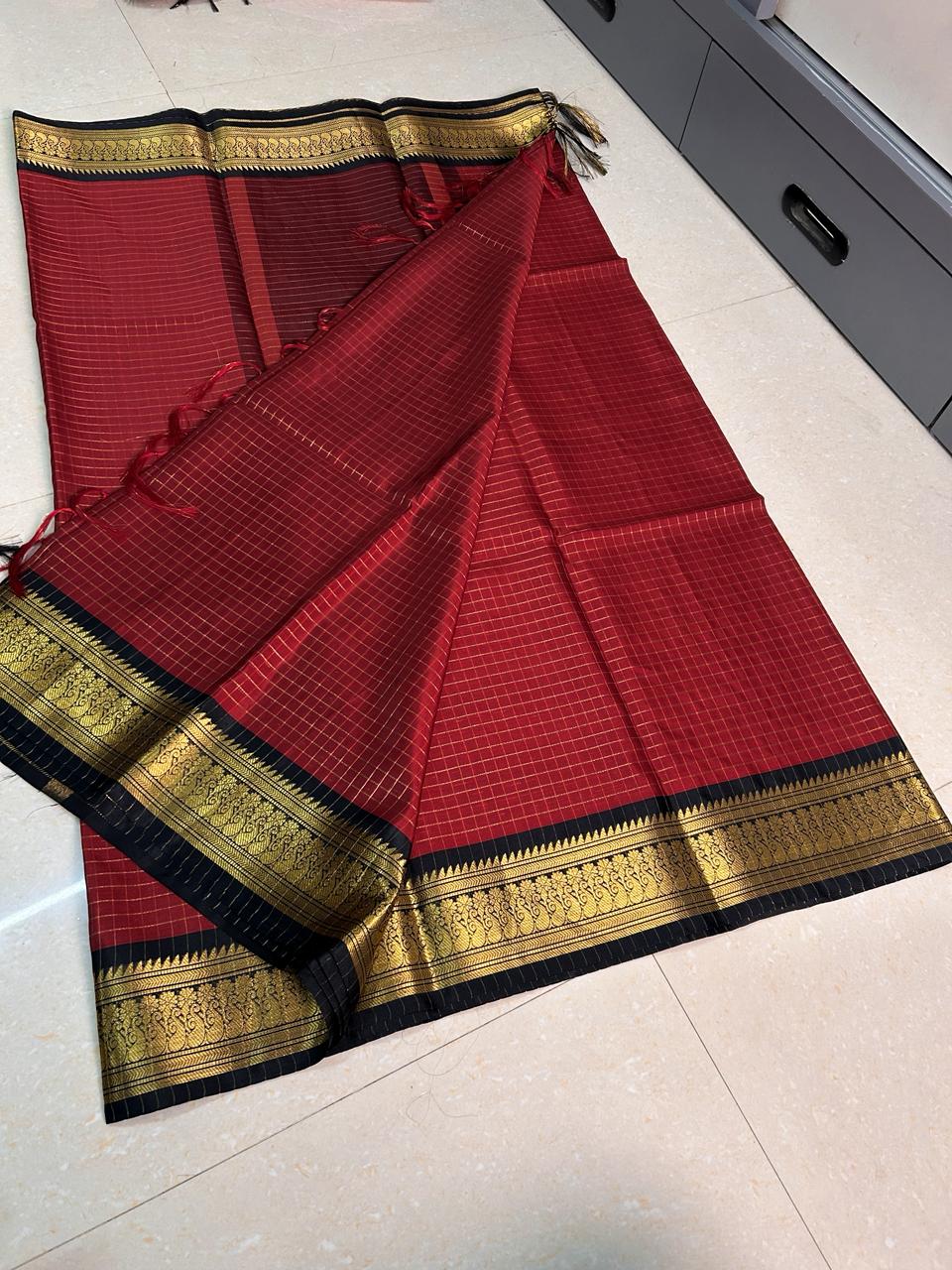 Red saree with gold and black border on a tiled floor