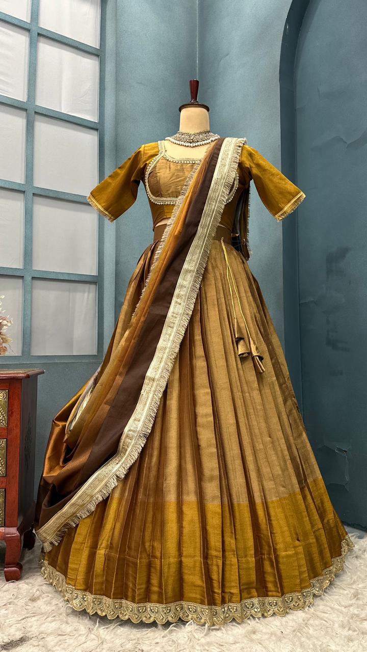 Traditional gold and brown saree on a mannequin against a blue wall.