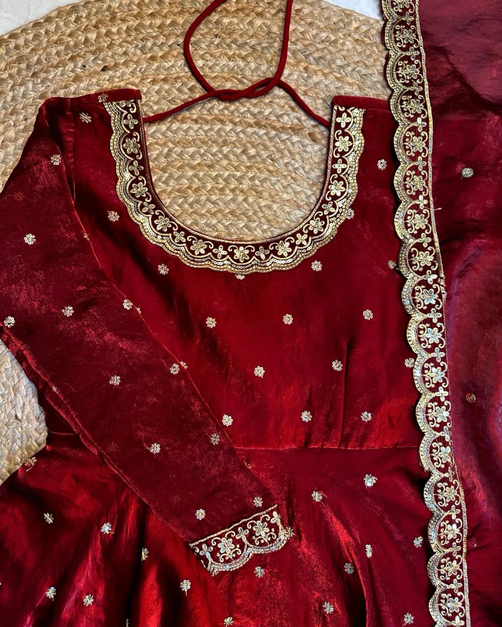 Maroon dress with gold embroidery on a textured surface