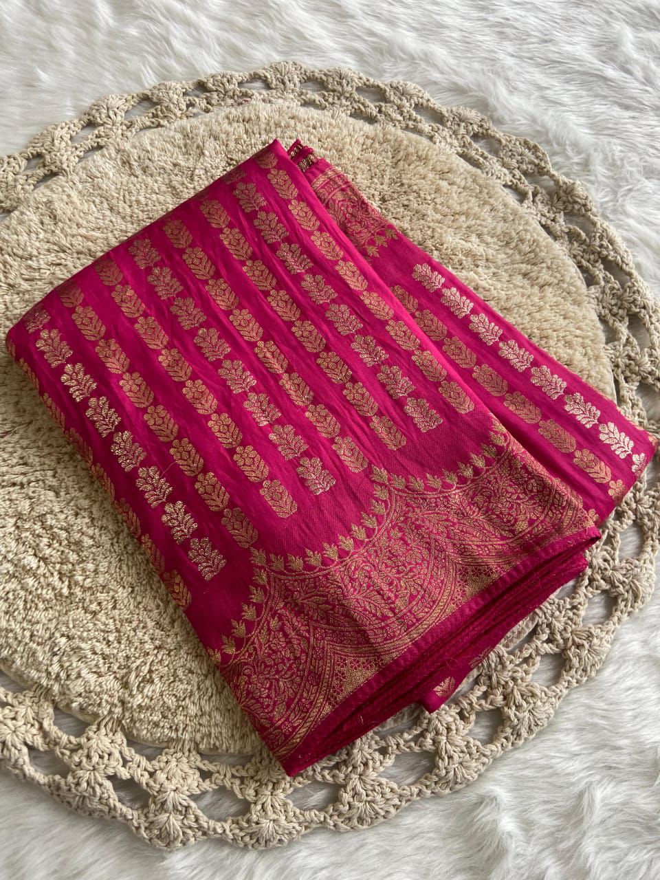 Pink saree with gold patterns on a texture surface
