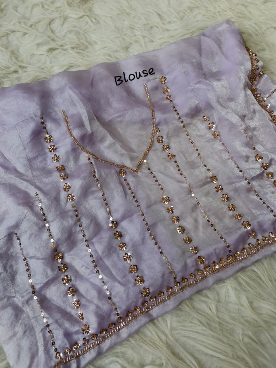 Lavender blouse with gold embellishments on a texture surface