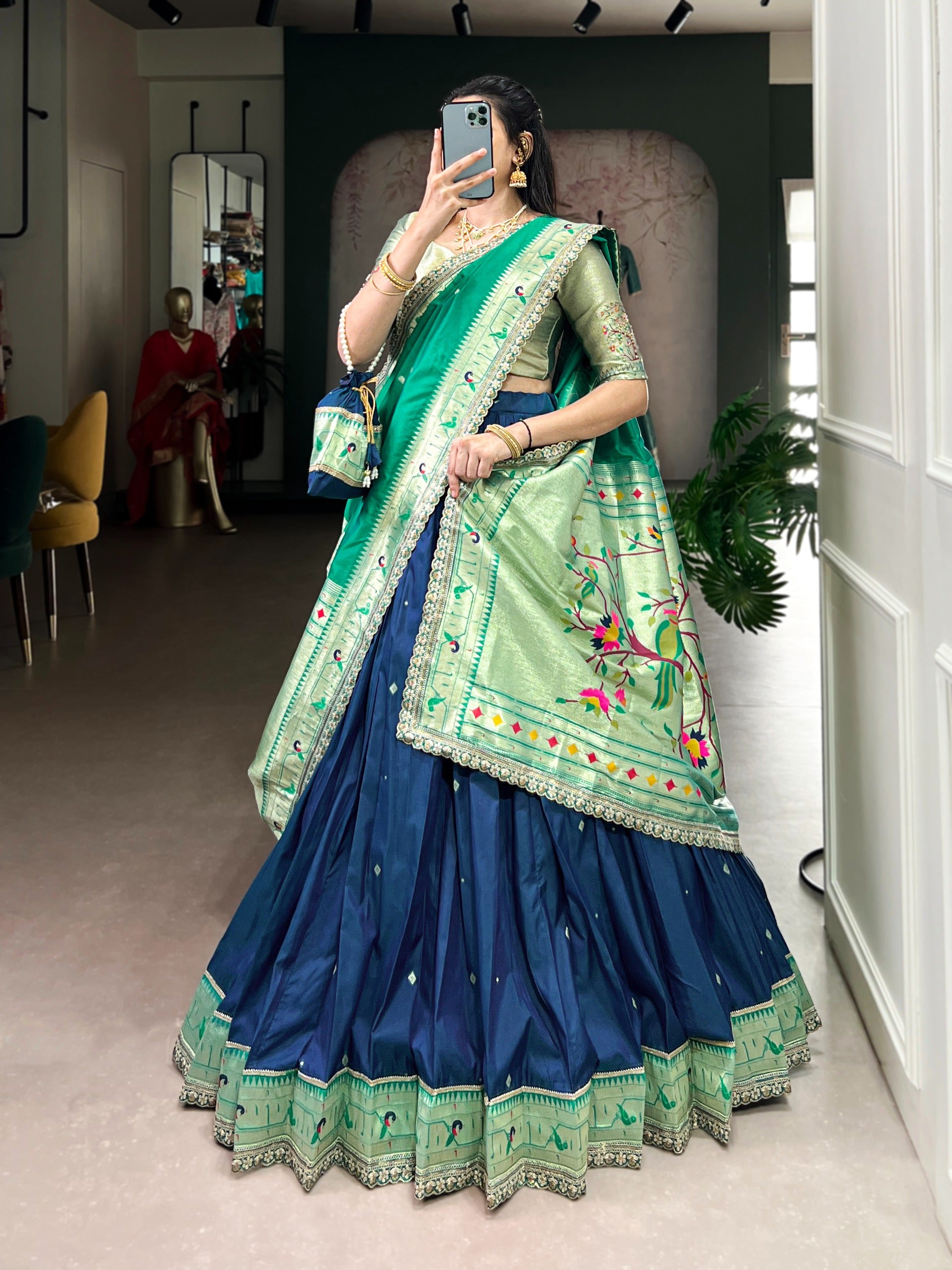 Person wearing a traditional navy blue outfit with embroidery, standing indoors.