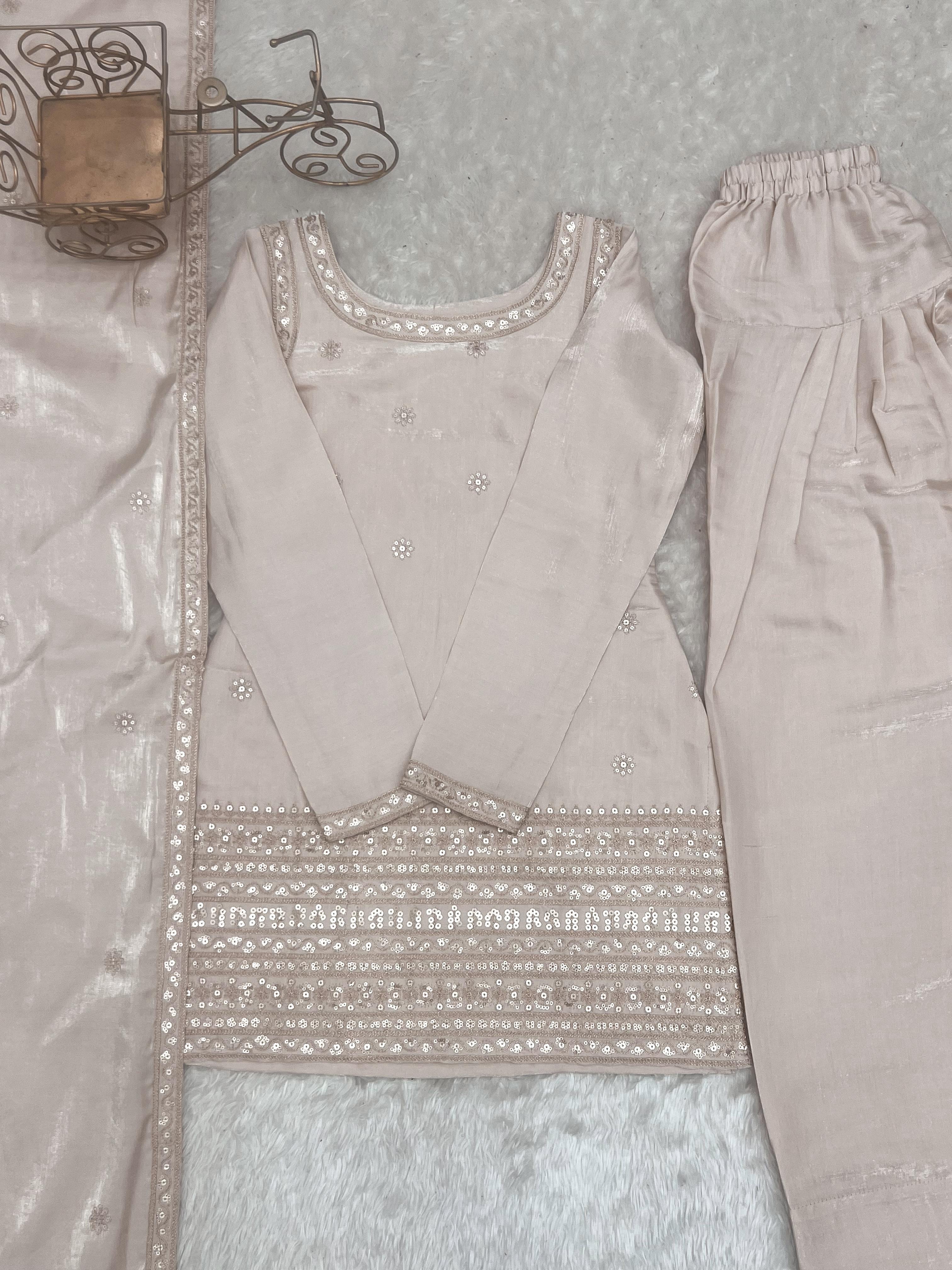 Beige traditional outfit with intricate embroidery on a textured surface