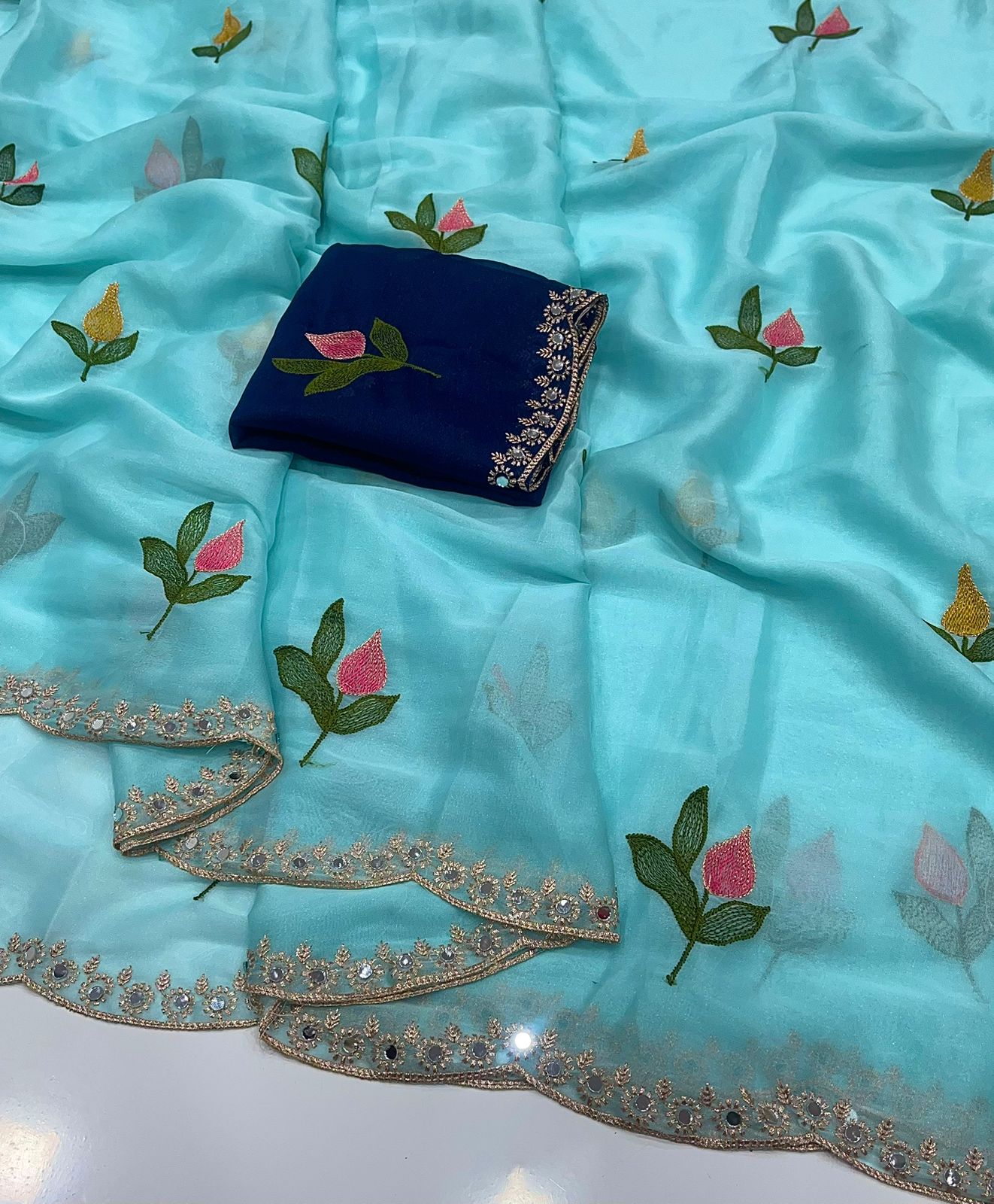 Sky blue fabric with floral embroidery and a blue embroidered pouch on a white background
