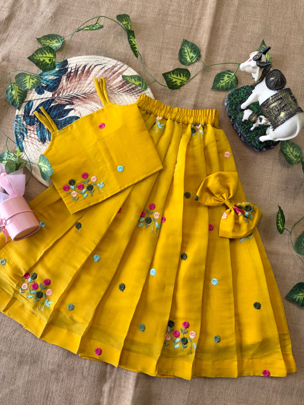 Mustard Yellow outfit with colorful embellishments on a textured surface with decorative elements.