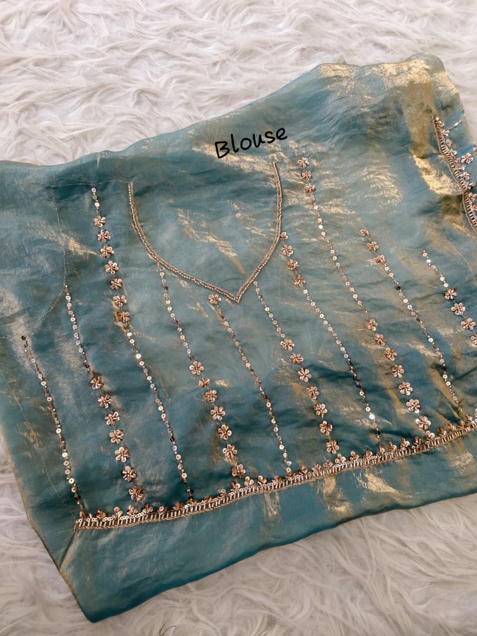 Turquoise Blue blouse with intricate detailing on a textured surface