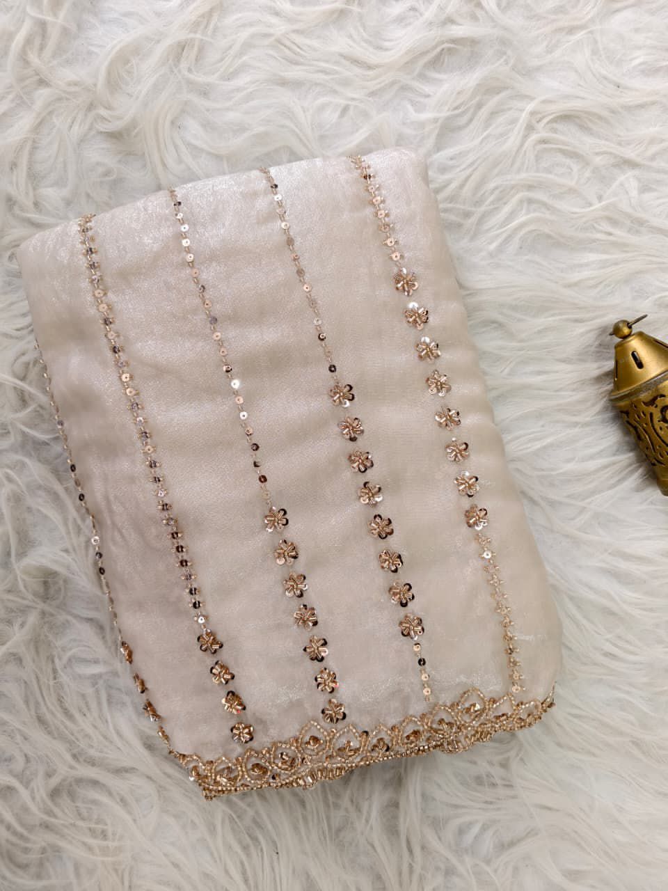 Cream saree with floral bead embroidery on a textured surface